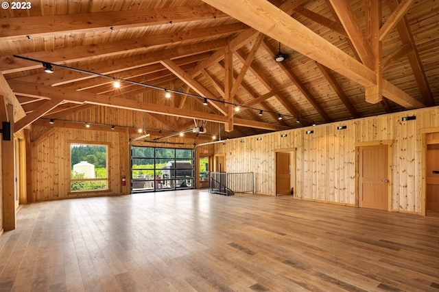 interior space with wooden walls, wooden ceiling, light wood-type flooring, and beam ceiling