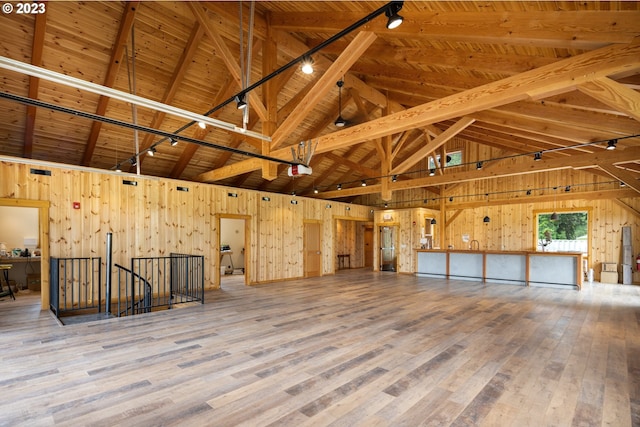 interior space with wooden walls, wood ceiling, light hardwood / wood-style floors, high vaulted ceiling, and beam ceiling