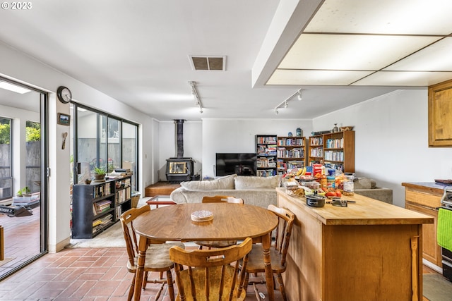 dining space with a wood stove and track lighting