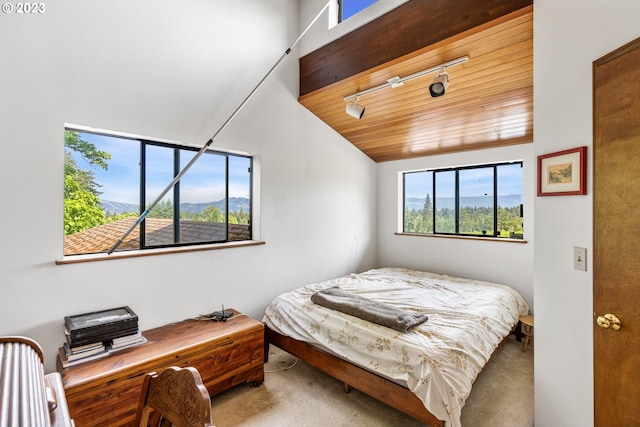 bedroom featuring wood ceiling, light colored carpet, rail lighting, and vaulted ceiling