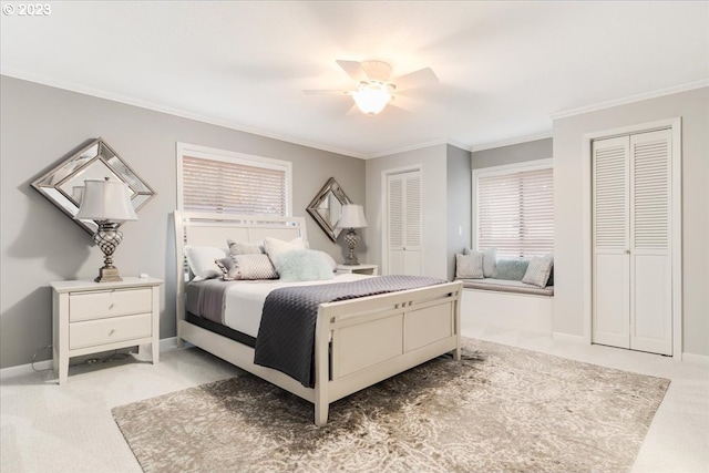 bedroom featuring ceiling fan, light carpet, and two closets