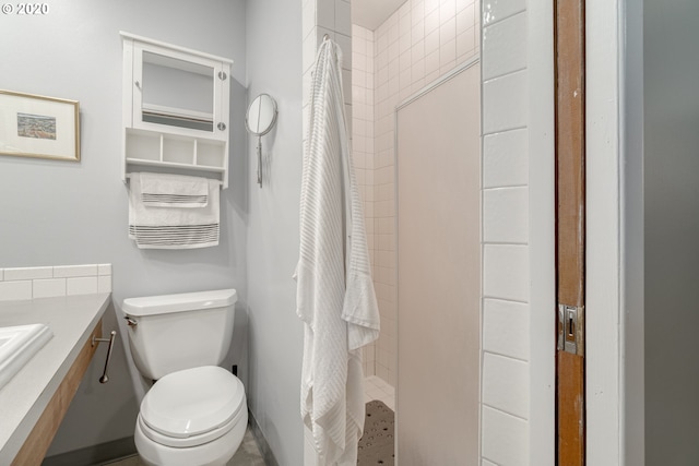 bathroom featuring tiled shower, toilet, and vanity