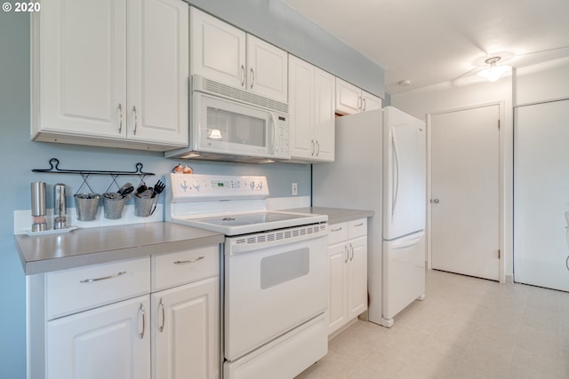 kitchen featuring light tile floors, white appliances, and white cabinetry