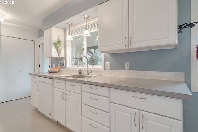 kitchen featuring white dishwasher, decorative light fixtures, white cabinetry, and sink