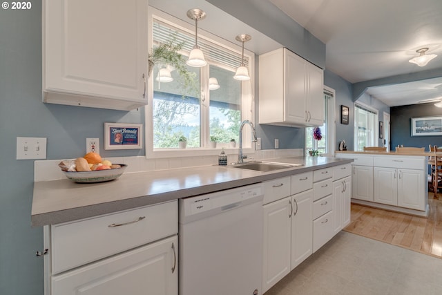 kitchen featuring light tile flooring, sink, white dishwasher, and white cabinets