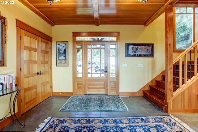 foyer entrance with a healthy amount of sunlight, wood ceiling, and dark tile patterned floors