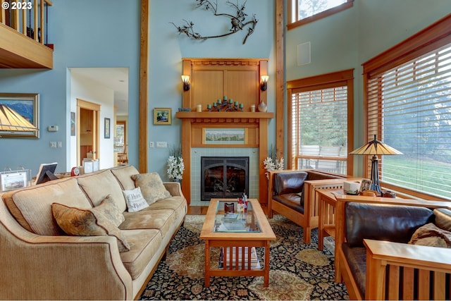 living room featuring a high ceiling, plenty of natural light, and a fireplace