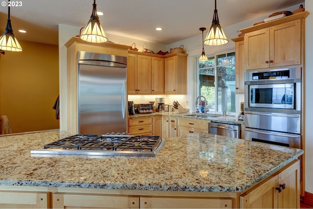 kitchen featuring light brown cabinets, appliances with stainless steel finishes, hanging light fixtures, and sink