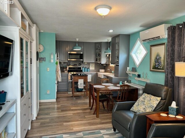 206 NE Front St, Prairie City, OR 97869 - dining area featuring dark hardwood / wood-style flooring, a textured ceiling, sink, and a wall unit AC