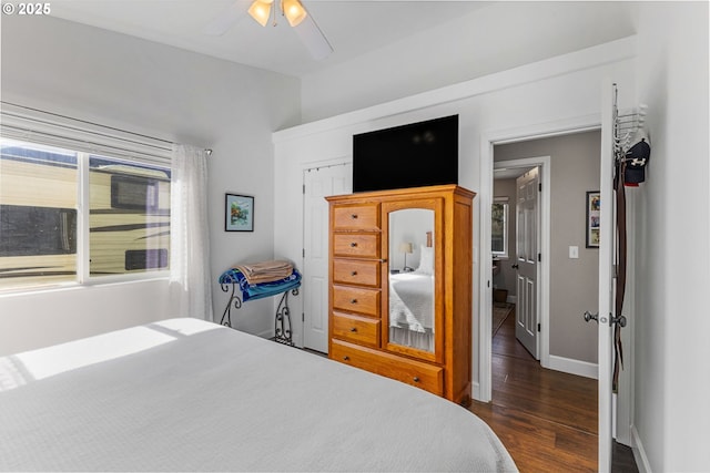 bedroom featuring dark wood finished floors, a closet, baseboards, and a ceiling fan