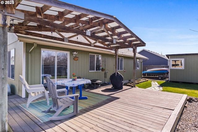 wooden terrace with a trampoline, an outdoor structure, a lawn, and a pergola