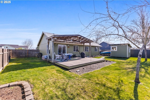 back of property featuring a storage unit, a wooden deck, an outbuilding, and a fenced backyard