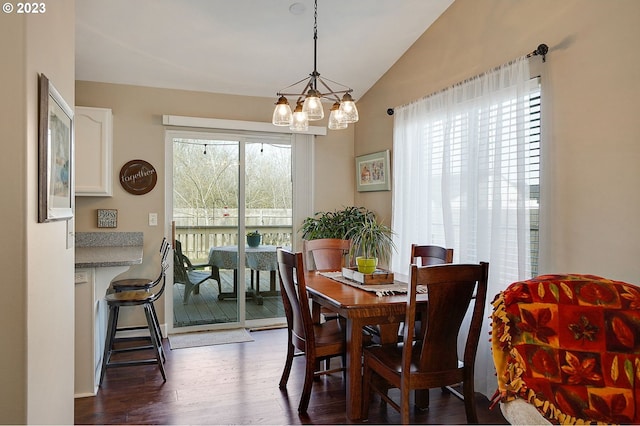 dining area with dark wood-style floors, a chandelier, a healthy amount of sunlight, and vaulted ceiling