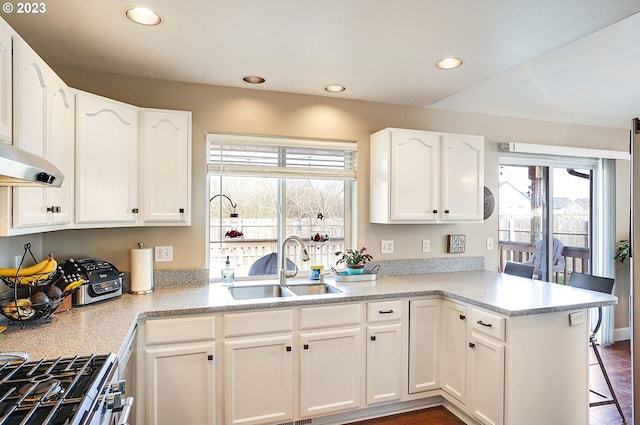 kitchen with white cabinets, light countertops, stainless steel range with gas cooktop, and a sink