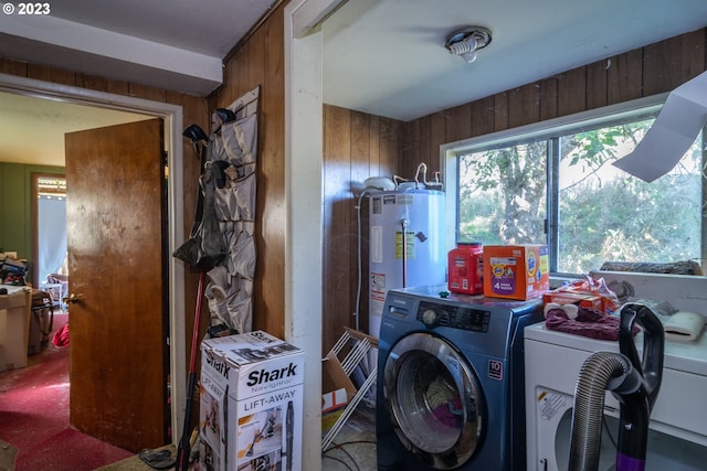 washroom with washing machine and clothes dryer, water heater, and wooden walls