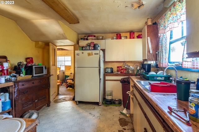 kitchen featuring white fridge, sink, light tile flooring, and wood counters