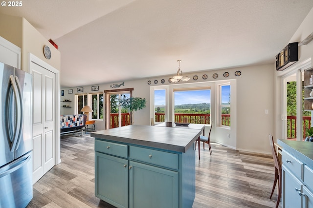 38225 Hiagua Ln N, Nehalem, OR 97131 - kitchen featuring freestanding refrigerator, light wood-type flooring, blue cabinets, dark countertops, and decorative light fixtures