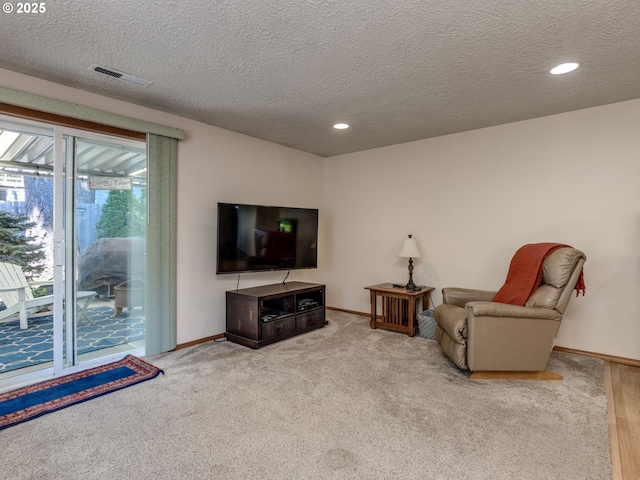 living room featuring carpet floors, a textured ceiling, visible vents, baseboards, and recessed lighting