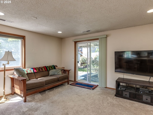 carpeted living area with a textured ceiling, baseboards, visible vents, and recessed lighting