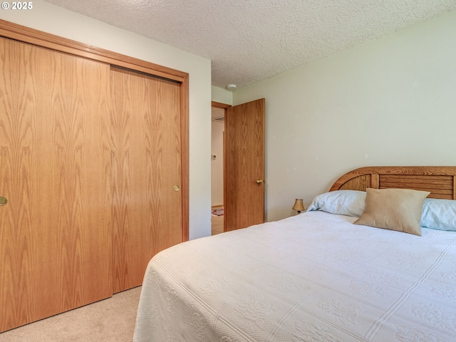 carpeted bedroom with a closet and a textured ceiling