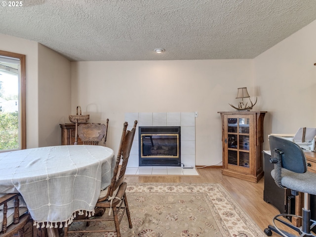 dining room with a fireplace, a textured ceiling, and wood finished floors