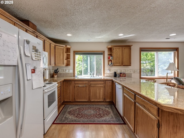 kitchen with a sink, open shelves, tile counters, a healthy amount of sunlight, and white appliances