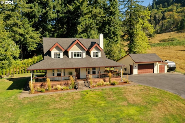 farmhouse featuring a garage, covered porch, an outdoor structure, and a front yard