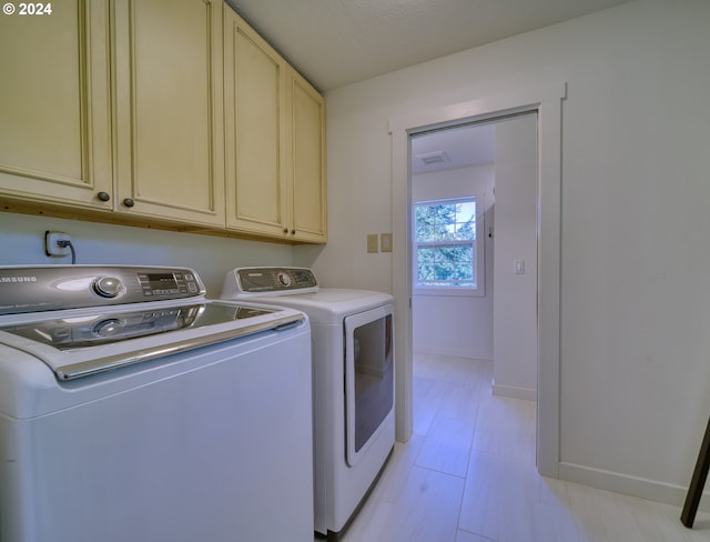 laundry area featuring washer and clothes dryer and cabinets