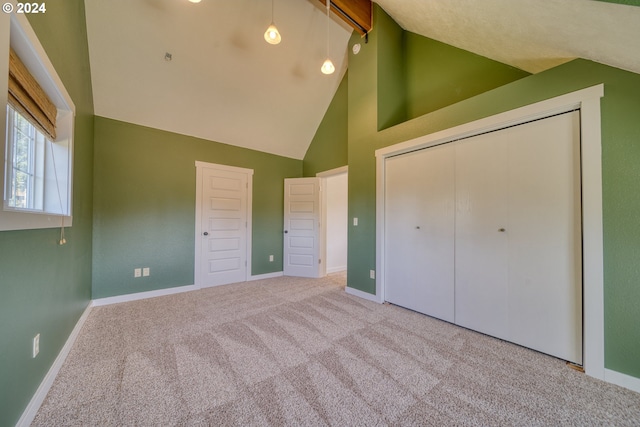 unfurnished bedroom with beam ceiling, light colored carpet, high vaulted ceiling, and a closet