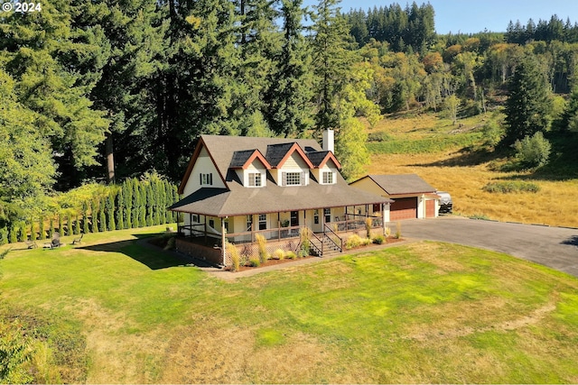 view of front of home with a porch, a garage, a front lawn, and an outdoor structure