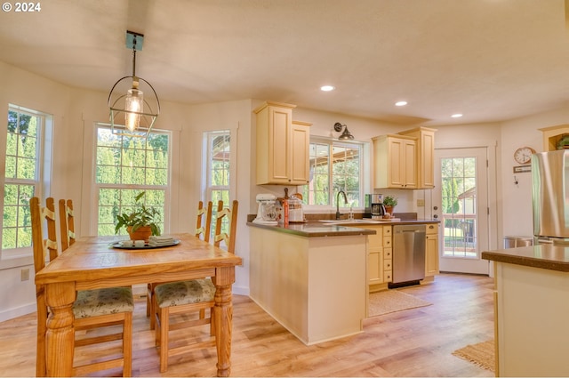 kitchen featuring sink, hanging light fixtures, light wood-type flooring, cream cabinetry, and stainless steel appliances