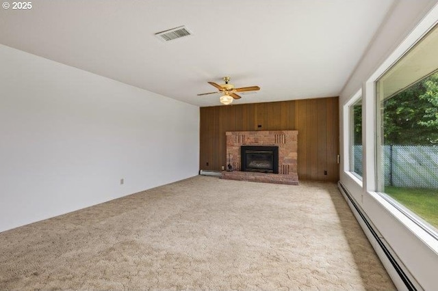 2107 Cove Ave, La Grande, OR 97850 - unfurnished living room with a baseboard radiator, wooden walls, ceiling fan, light carpet, and a brick fireplace