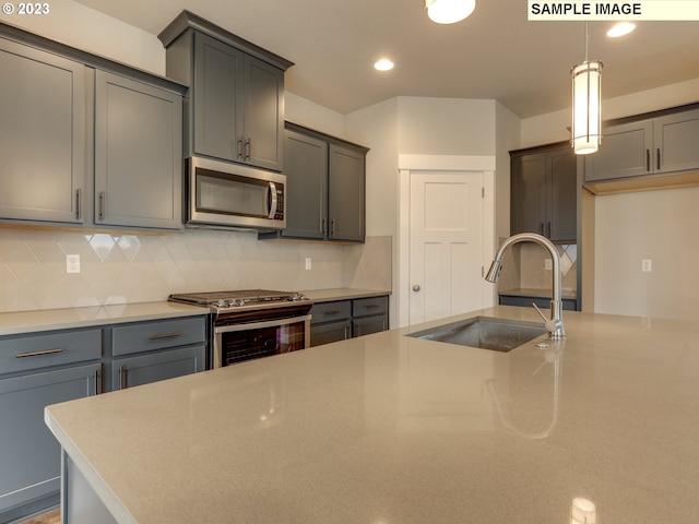 kitchen with hanging light fixtures, appliances with stainless steel finishes, gray cabinets, sink, and tasteful backsplash