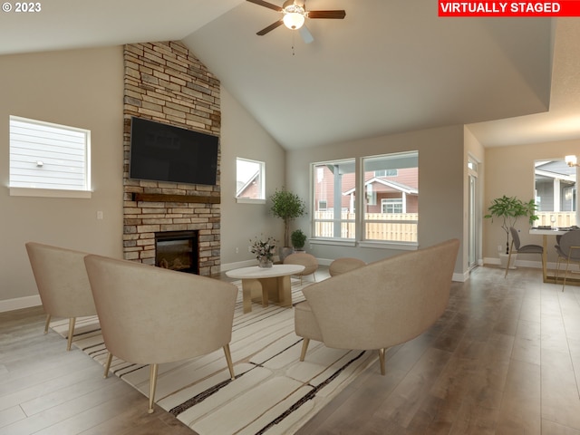 living room with a stone fireplace, high vaulted ceiling, ceiling fan, and hardwood / wood-style floors