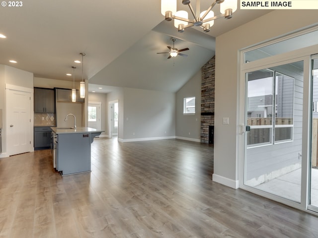 unfurnished living room featuring light hardwood / wood-style floors, sink, lofted ceiling, and a fireplace