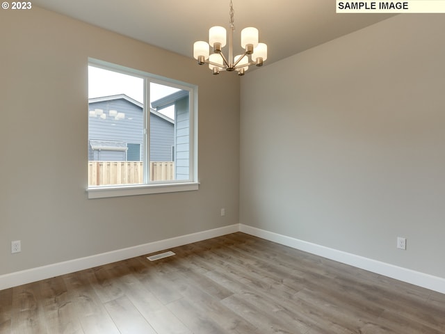 empty room with an inviting chandelier and wood-type flooring