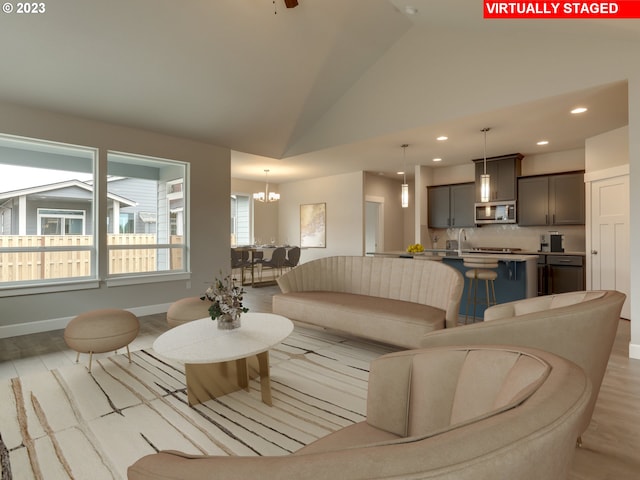 living room featuring light hardwood / wood-style floors, sink, high vaulted ceiling, and a notable chandelier