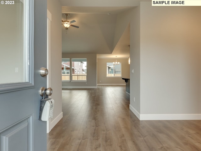 interior space with ceiling fan with notable chandelier, vaulted ceiling, and hardwood / wood-style floors