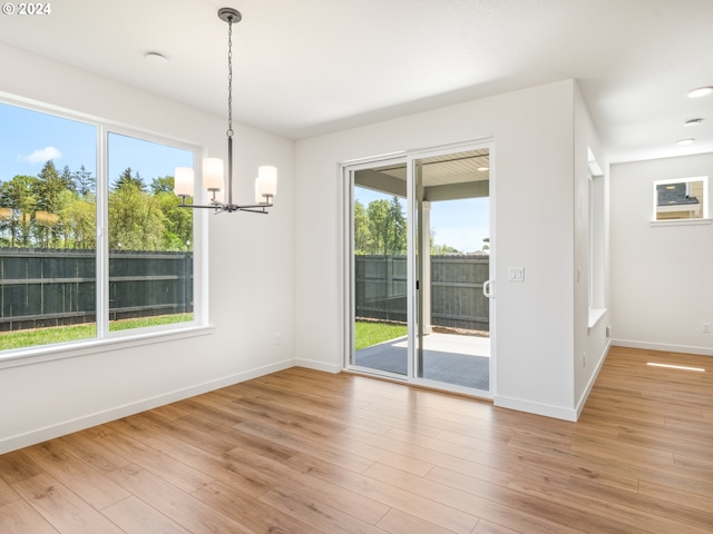 unfurnished dining area with light hardwood / wood-style flooring and a chandelier