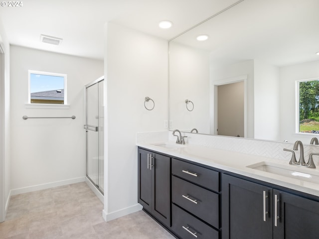 bathroom with a shower with shower door, a healthy amount of sunlight, and vanity