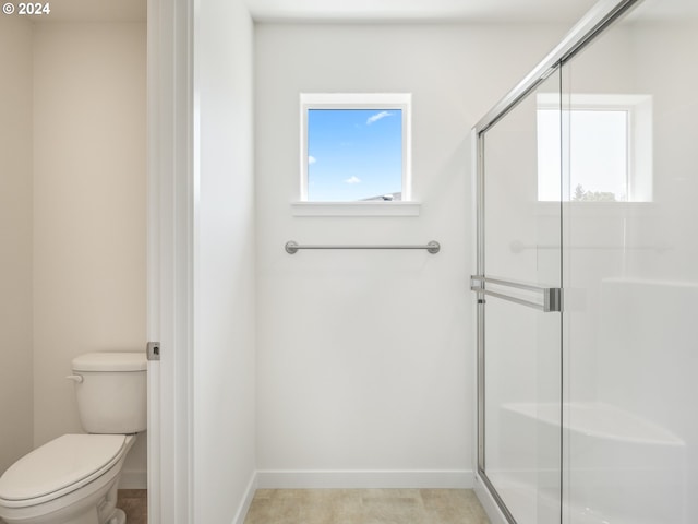 bathroom with a shower with shower door and toilet