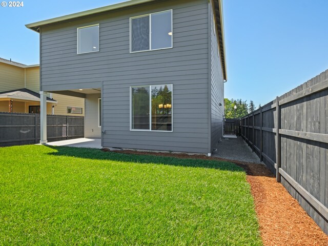 back of property with a patio area and a lawn