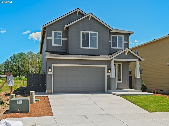 craftsman-style home featuring a garage, covered porch, and a front lawn