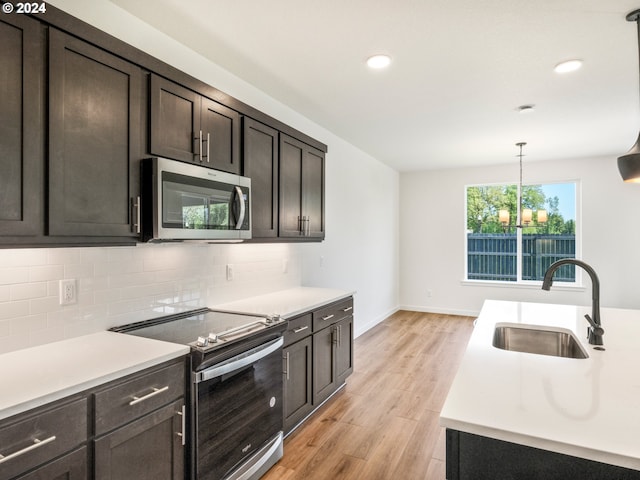 kitchen with decorative light fixtures, decorative backsplash, appliances with stainless steel finishes, dark brown cabinets, and sink