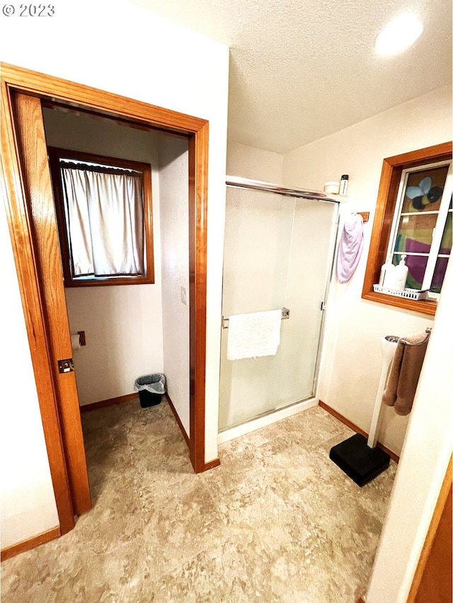 bathroom featuring a textured ceiling and a shower with shower door