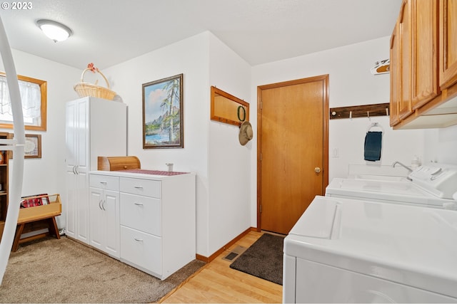 washroom with separate washer and dryer, light hardwood / wood-style flooring, and cabinets