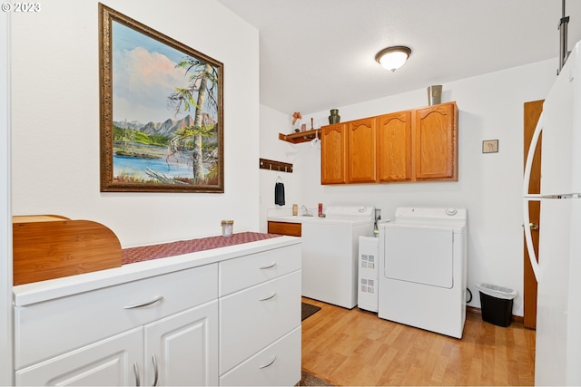 laundry room featuring cabinets, light wood-type flooring, separate washer and dryer, and sink