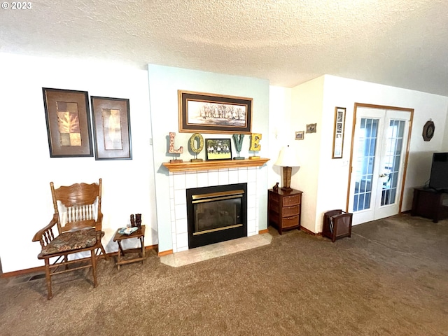 sitting room featuring dark carpet, a textured ceiling, a tile fireplace, and french doors