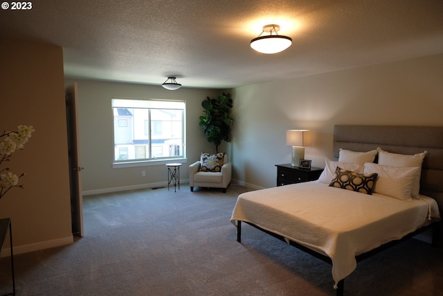 bedroom with dark carpet and a textured ceiling