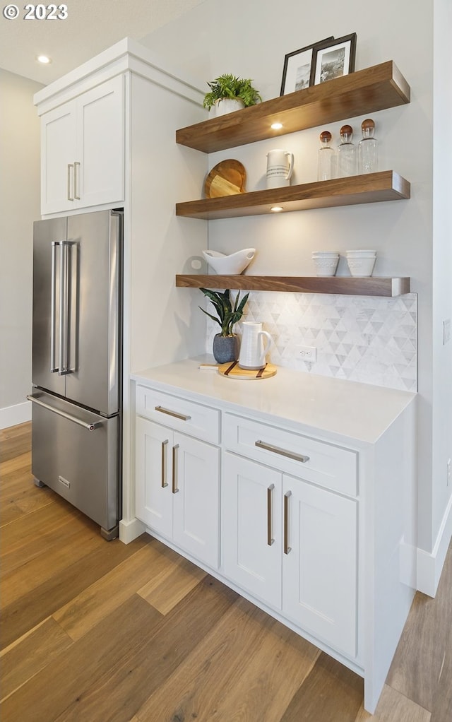 bar featuring light hardwood / wood-style flooring, white cabinetry, and high end refrigerator